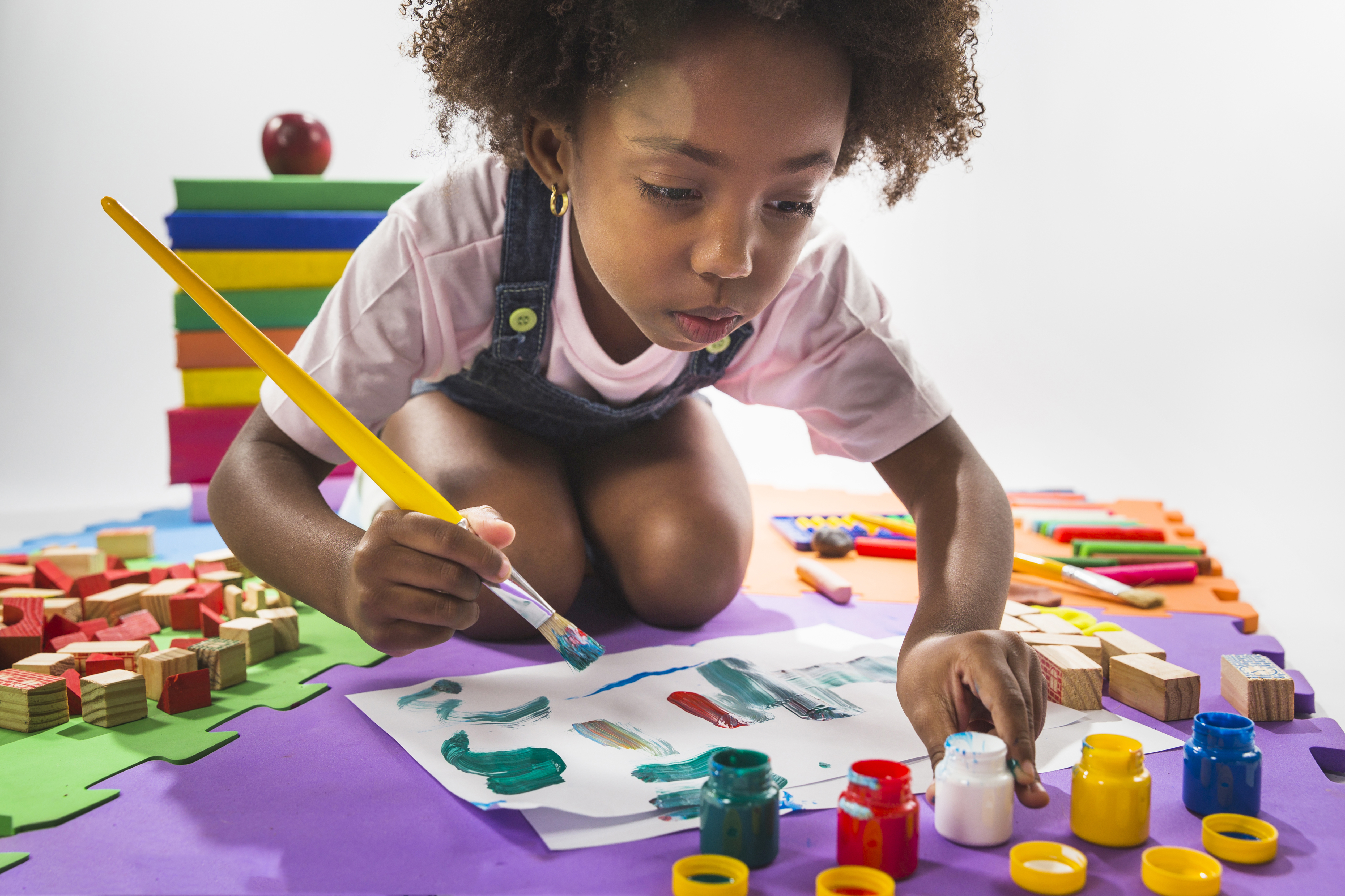 A young girl reading book and playing on the floor.